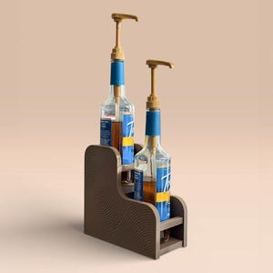 May include: Two clear glass bottles with syrup pumps, displayed on a brown wooden organizer. The bottles have blue and white labels. The organizer has a curved design with a circular pattern.