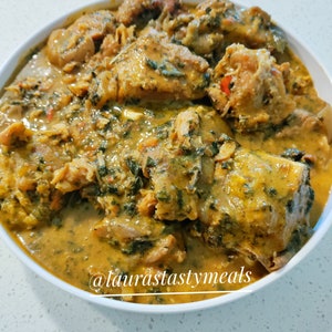 May include: A white bowl filled with a yellow and green stew with chunks of meat. The text "@laurastastymeals" is at the bottom of the bowl.