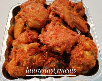 May include: A silver aluminum container filled with red-colored chicken pieces. The chicken is coated in a spicy sauce and is ready to eat. The container has the text "laurastastymeals" printed on the bottom.