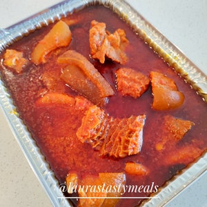 May include: A close-up of a silver aluminum container filled with a red stew. The stew contains chunks of meat and vegetables. The text "@laurastastymeals" is visible in the bottom right corner of the image.