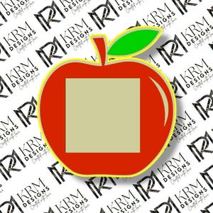 May include: A red apple-shaped design with a green leaf and a yellow outline. The apple has a square, light tan center. The background features a repeating pattern of the text "KRM DESIGNS Crafted with love."