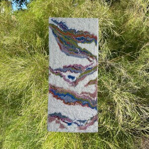 May include: A white rug with a colorful abstract design. The design features swirls of blue, green, red, and pink.