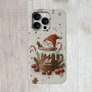 May include: A white phone case featuring a winter holiday design. A cartoon gnome is sat in a mug of hot chocolate with the text "Hot Chocolate". The background is white with snowflakes and red berries.