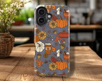 May include: A phone case with a fall-themed pattern featuring pumpkins, sunflowers, coffee cups, candles, and mushrooms on a gray background. The case is on a wooden table.