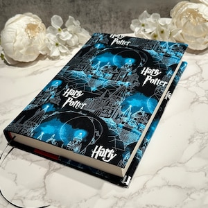 May include: A black book cover with a blue and white pattern of Hogwarts castle and the words "Harry Potter" repeated throughout.