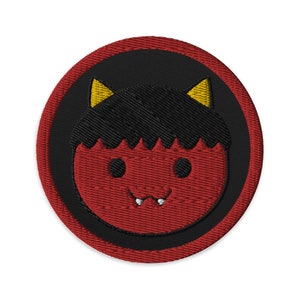May include: A red and black embroidered patch with a cartoon image of a red-faced, black-haired, smiling demon with yellow horns.