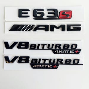 Puede incluir: Emblemas Mercedes-Benz E63S AMG V8 Biturbo 4MATIC+ negros y rojos. Los emblemas están hechos de plástico negro brillante con letras plateadas y detalles rojos.