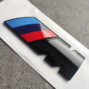 BMW M emblem, (rear) 90 x 30 mm NEW black glossy lettering, self-adhesive, sticker, new in foil, trunk