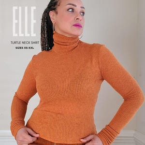 May include: An orange ribbed turtleneck shirt with long sleeves. The shirt is part of the "ELLE" collection, available in sizes XS-XXL. The text "KEECHII B STYLE" is at the top of the image.