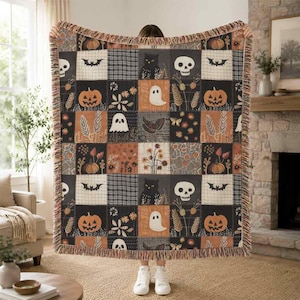 May include: A woven throw blanket featuring a patchwork design with Halloween-themed motifs including black cats, skulls, ghosts, pumpkins, bats, and floral patterns in shades of orange, black, cream, and brown, finished with a fringed edge.