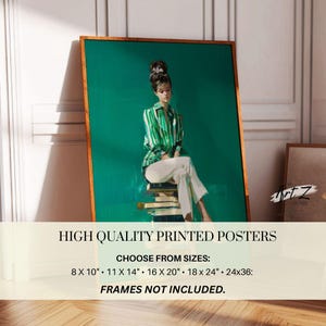 May include: A framed art print featuring a woman in a green and white striped shirt and white pants, seated on a stack of books. The artwork has a teal background and a wooden frame. The print is labeled "HIGH QUALITY PRINTED POSTERS".