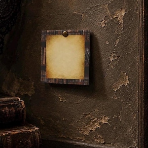 May include: A square notepad featuring a printed border of vintage book spines on shelves. The center of the notepad is a blank, parchment-colored sheet with a weathered, aged appearance. A single brass-colored metal pin secures the top center.