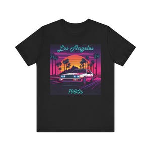 May include: Black t-shirt with a retro-style graphic of a white car driving through a sunset scene with palm trees. The graphic includes the text "Los Angeles 1980s".