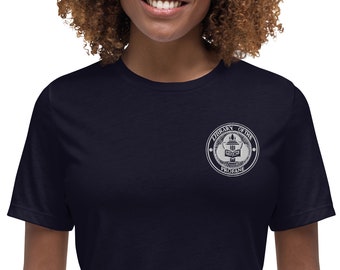 May include: A navy blue t-shirt with a white embroidered patch on the left chest. The patch features a circular design with the text "Library of the Profane" inside.