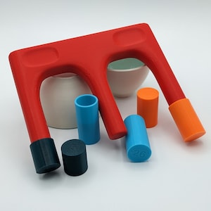 Puede incluir: Un juguete de plástico rojo con tres arcos y cinco bloques cilíndricos de colores. Los bloques están etiquetados con números. El juguete está diseñado para apilar y clasificar.