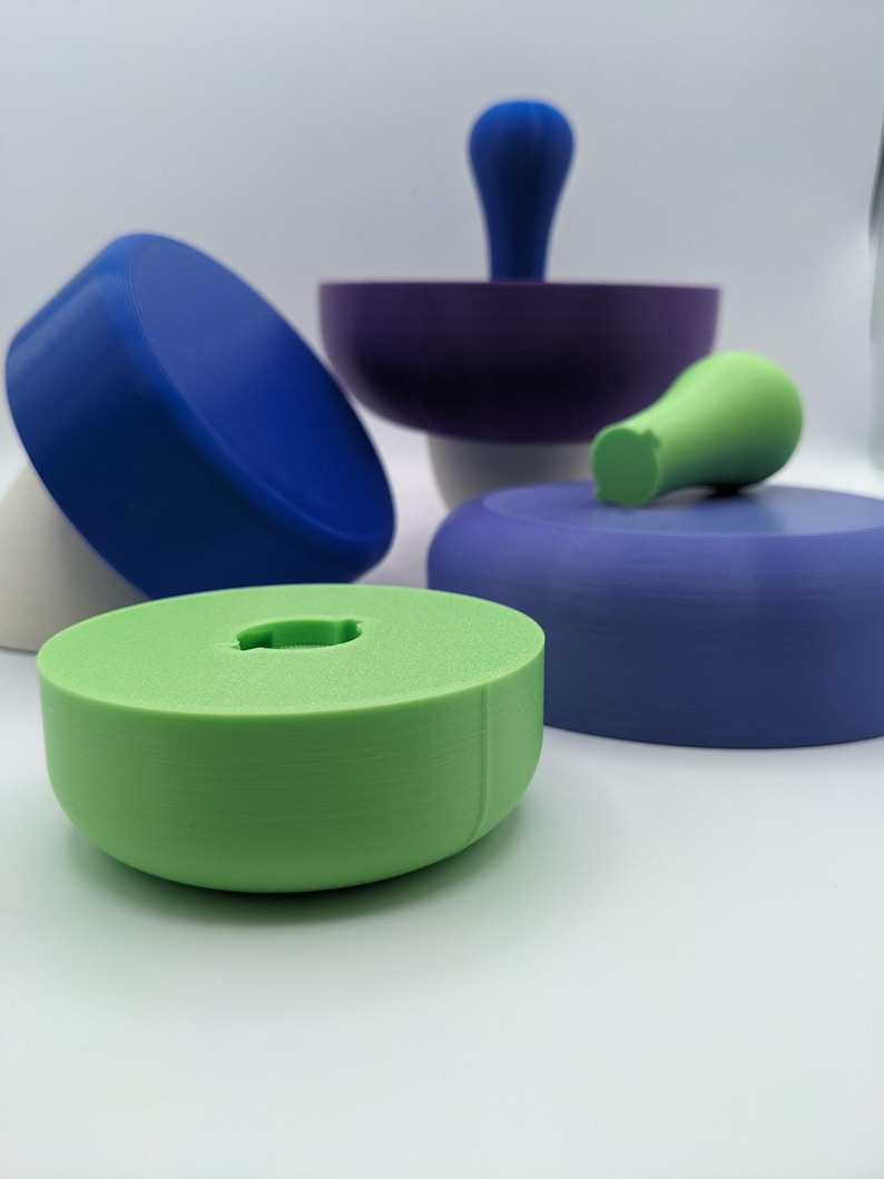 Puede incluir: Un conjunto de juguetes apilables de colores hechos de pl&aacute;stico. Los juguetes tienen forma de hongo con tapas de diferentes colores y tallos blancos. El conjunto incluye un hongo azul, verde y morado.