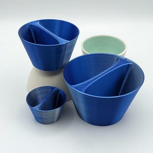 May include: Three blue ceramic bowls with a divided section. The bowls are different sizes and have a matte finish.