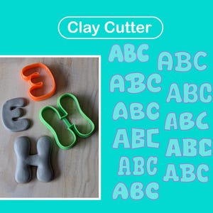 Könnte beinhalten: Ein Set aus Ton-Ausstechformen mit einem orangefarbenen E-Ausstecher, einem grünen H-Ausstecher sowie zwei geformten Tonbuchstaben E und H in Grau. Das Bild enthält den Text Clay Cutter und mehrfach die Buchstaben ABC in Hellblau.