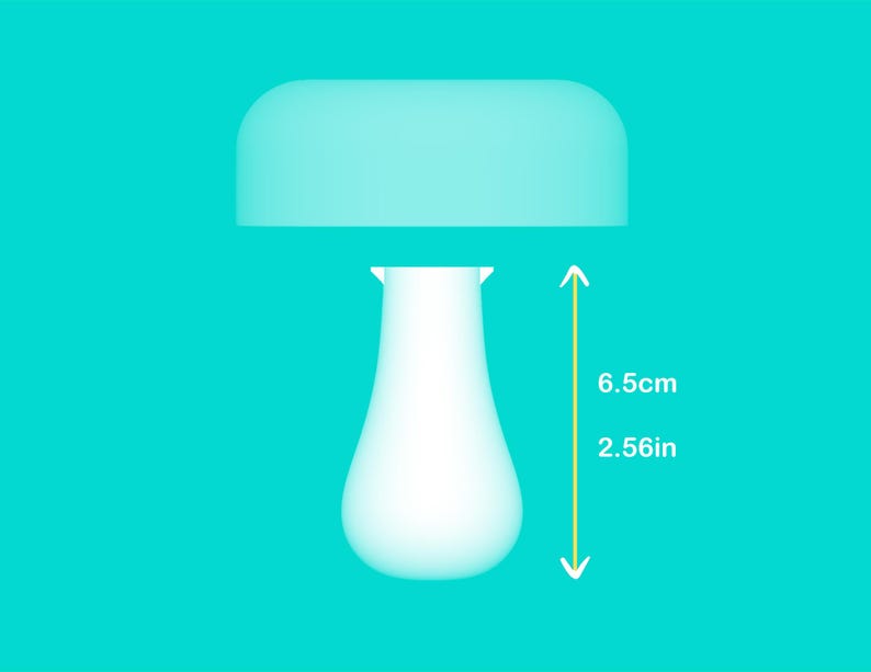 Peut inclure: Une lampe blanche en forme de champignon avec un dessus arrondi et une base en forme de goutte d'eau. La lampe mesure 6,5 cm (2,56 pouces) de haut. Le fond est de couleur turquoise uni.