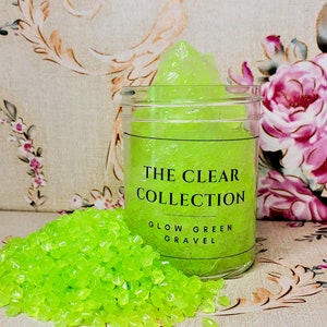 4oz of clear slime with green glow in the dark stones inside, inside a jar with a clear label, Glow Green Gravel.