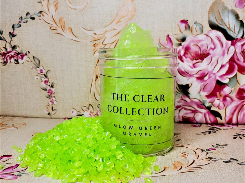 4oz of clear slime with green glow in the dark stones inside, inside a jar with a clear label, Glow Green Gravel.