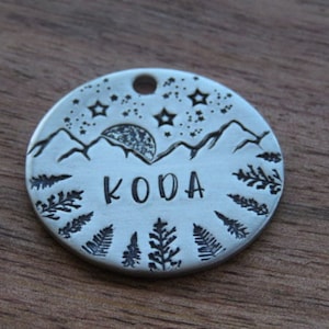 Puede incluir: Chapa redonda de plata para mascotas con un diseño de montaña, luna y estrellas. La chapa está grabada con el nombre "KODA".