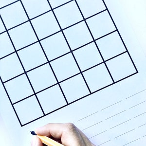 May include: A blank grid with 36 squares, drawn in black ink on white paper. A hand is holding a yellow pencil and writing on a lined section below the grid.