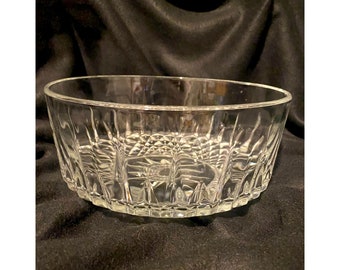 May include: A clear glass bowl with a textured, diamond-shaped pattern. The bowl is round and has a wide rim.