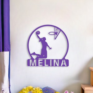 Peut inclure: Décoration murale en métal violet représentant une silhouette de basketteuse tirant au panier avec le nom "MELINA" en dessous.