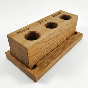 Wooden toothbrush holder for 3 toothbrushes with name engraved above each spot.