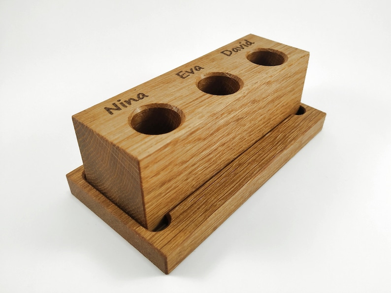 Wooden toothbrush holder for 3 toothbrushes with name engraved above each spot.