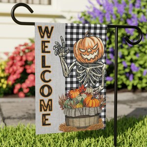 May include: A Halloween-themed welcome flag featuring a skeleton holding a pumpkin and a basket of pumpkins. The flag is black and white checked with the word "WELCOME" in black lettering.