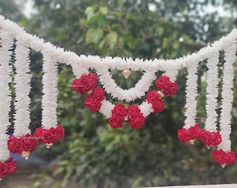 May include: White and red floral garland with red rose accents. The garland is made of white fabric and has a cascading design. It is perfect for decorating a home or event.