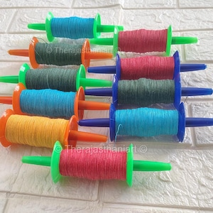 May include: A close-up of ten colorful spools of string with green handles. The spools are arranged in a row, with the handles facing the viewer. The spools are made of plastic and have a variety of colors, including red, blue, green, yellow, and orange.