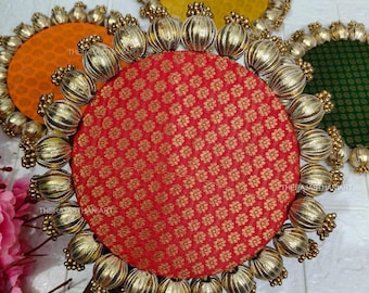 Puede incluir: Colección de manteles individuales redondos decorativos en rojo, naranja, amarillo y verde. Cada mantel individual presenta un centro de tela estampada y está rodeado de adornos dorados con cuentas. Los manteles individuales tienen un diseño tradicional.