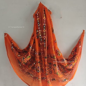 Puede incluir: Una bufanda naranja de gasa con bordados intrincados y trabajo de espejo. La bufanda presenta un diseño floral con acentos coloridos.  ©Therajasthanianart ©