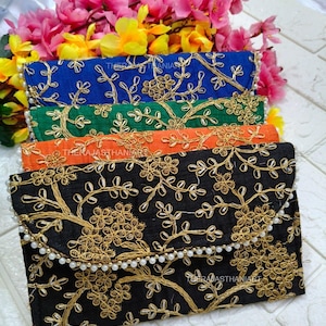 Peut inclure: Plusieurs pochettes brodées en bleu, vert, orange et noir. Chaque pochette présente une broderie florale dorée et un bord perlé. Le texte "THERAJASTHANIART" est visible. Des fleurs roses et jaunes sont en arrière-plan.