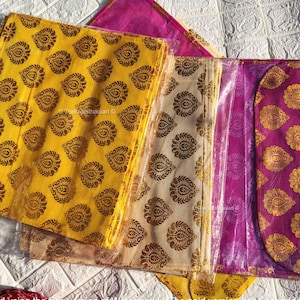 May include: A set of three fabric gift bags with a floral pattern. The bags are yellow, beige, and pink. The bags are made of a sheer fabric and have a delicate floral design.
