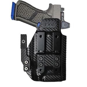 May include: A black carbon fiber holster with a semi-automatic pistol. The pistol has a gray slide, a blue magazine base, and a textured grip. The holster has the text "EYV" and two black clips.