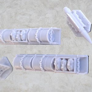 Op de afbeelding: Een set van vijf witte plastic modelonderdelen voor een militair vliegtuig. De onderdelen omvatten een raket, een vleugel en drie brandstoftanks.
