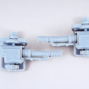 May include: Two gray plastic miniature cannons with a detailed design. The cannons are mounted on a base and have a barrel that can be rotated.