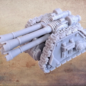 Puede incluir: Un modelo de tanque en miniatura de color gris claro con tres cañones grandes. El tanque tiene orugas detalladas y un diseño complejo, lo que sugiere un tema militar o de ciencia ficción. El modelo está hecho de un material sólido y es probablemente un artículo de colección o de hobby.