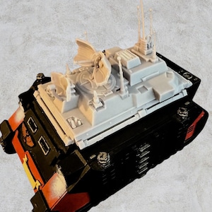 May include: A gray plastic model of a tank with a large radar dish on top. The tank is painted black and red with gold accents.
