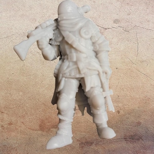 Puede incluir: Una figura en miniatura de color gris claro de un guerrero, sosteniendo un rifle sobre su hombro. La figura lleva armadura, una bufanda y botas. La miniatura está sobre una superficie texturizada.