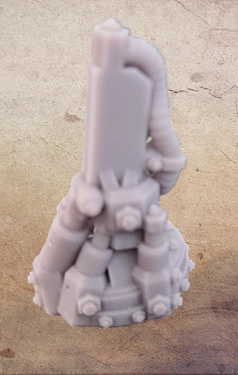 May include: A light gray, 3D-printed miniature, possibly for a tabletop game. The model features a cylindrical body with various attached mechanical components, including tubes and circular details. The base is round.