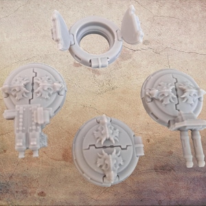 Peut inclure: Ensemble de composants miniatures gris clair imprimés en 3D, comprenant des trappes circulaires avec des motifs ornementaux en forme de dragon et une pièce en forme d'anneau avec un couvercle à charnière. Les pièces sont disposées sur une surface texturée et beige.