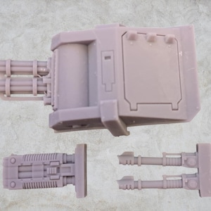 May include: A set of three gray plastic model pieces for a sci-fi vehicle. The pieces include a large turret with a barrel and two smaller barrels, a smaller turret with a barrel, and a long barrel.