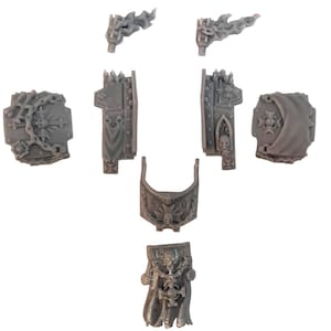 May include: A set of grey plastic miniature parts for a model kit. The parts are shaped like armor plates and have intricate details, including chains, skulls, and flames.