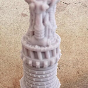 May include: A light purple, intricately detailed, 3D-printed sculpture resembling a stylized tower. The design features multiple levels with architectural elements and a rounded top. The sculpture is approximately 5 inches tall.