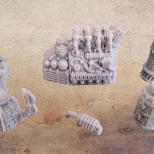 May include: A selection of grey, detailed miniature machine parts, including a complex engine block, cylindrical components, and other mechanical elements. The pieces are arranged on a textured, neutral-toned surface, suggesting a model-making or hobbyist theme.